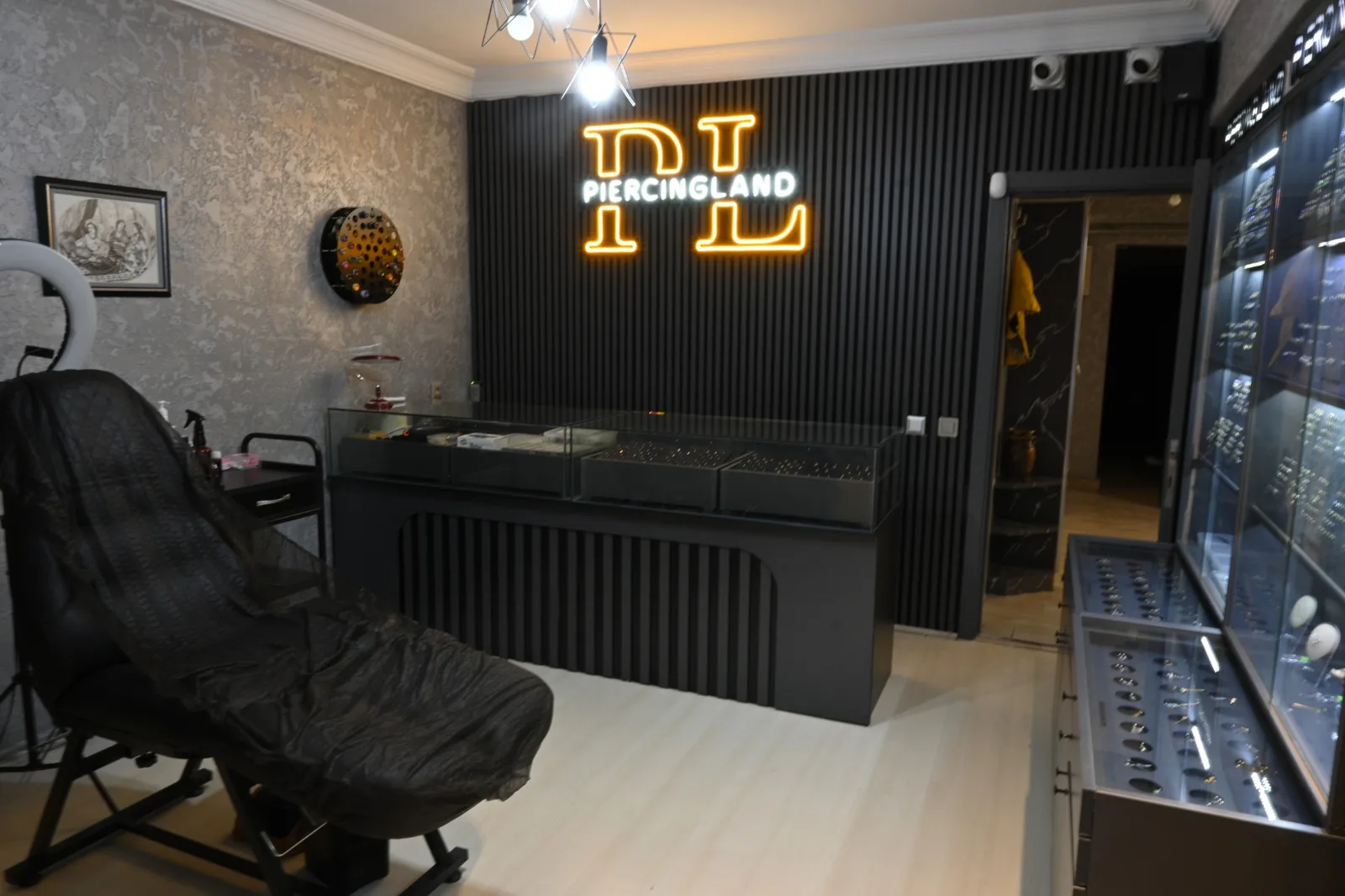 The PiercingLand neon sign, the chair and the display case